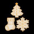 Three white holiday trays with gold trim and patterns: a Christmas tree, a stocking and a snowflake, seen from above on black