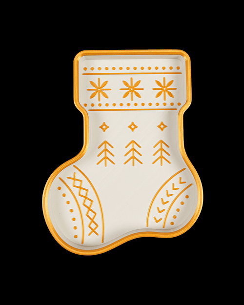 Top view of a white stocking tray with a gold rim and gold Nordic pattern of snowflakes, small trees, and stitches, on black