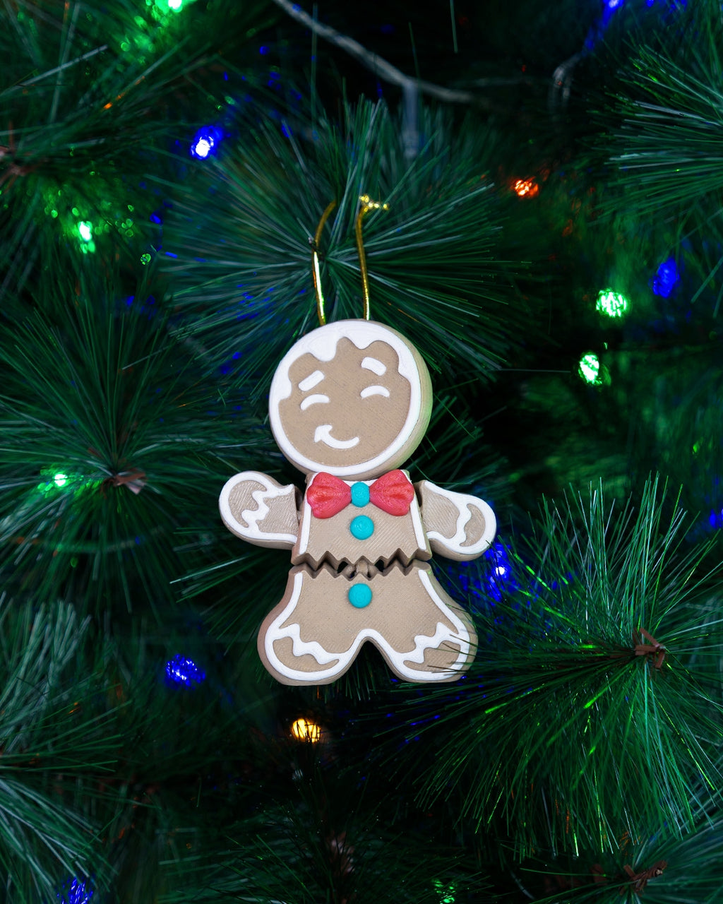 Gingerbread man Christmas ornament hanging from its gold cord on a lit Christmas tree
