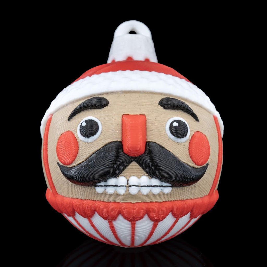 Nutcracker Christmas ornament, 3D printed, front view: red hat with white trim, black mustache, red cheeks and printed hanging loop, on a black background