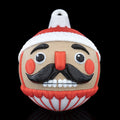 Nutcracker Christmas ornament, 3D printed, front view: red hat with white trim, black mustache, red cheeks and printed hanging loop, on a black background
