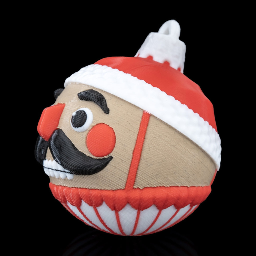 Side profile of the Nutcracker Christmas ornament with red hat, white trim and printed top loop, on a black background