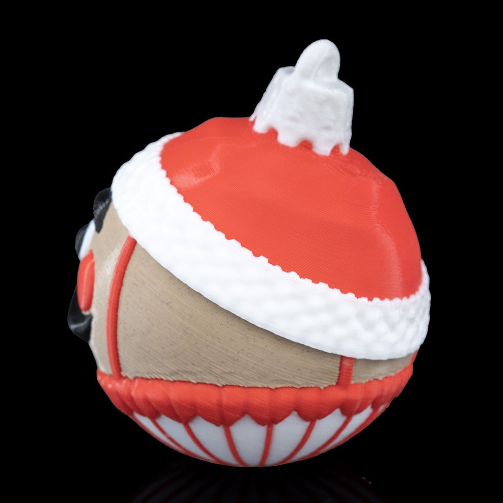 Back-side view of the Nutcracker Christmas ornament showing the red hat, textured white trim and printed loop, on a black background