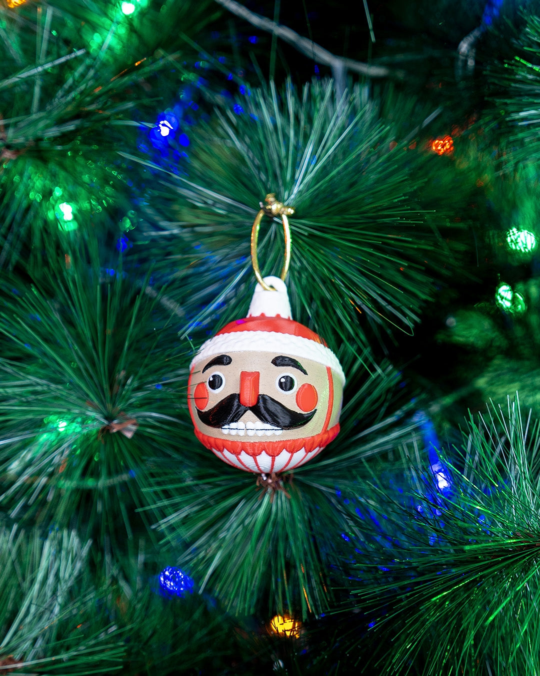 Nutcracker Christmas ornament hanging on a lit Christmas tree