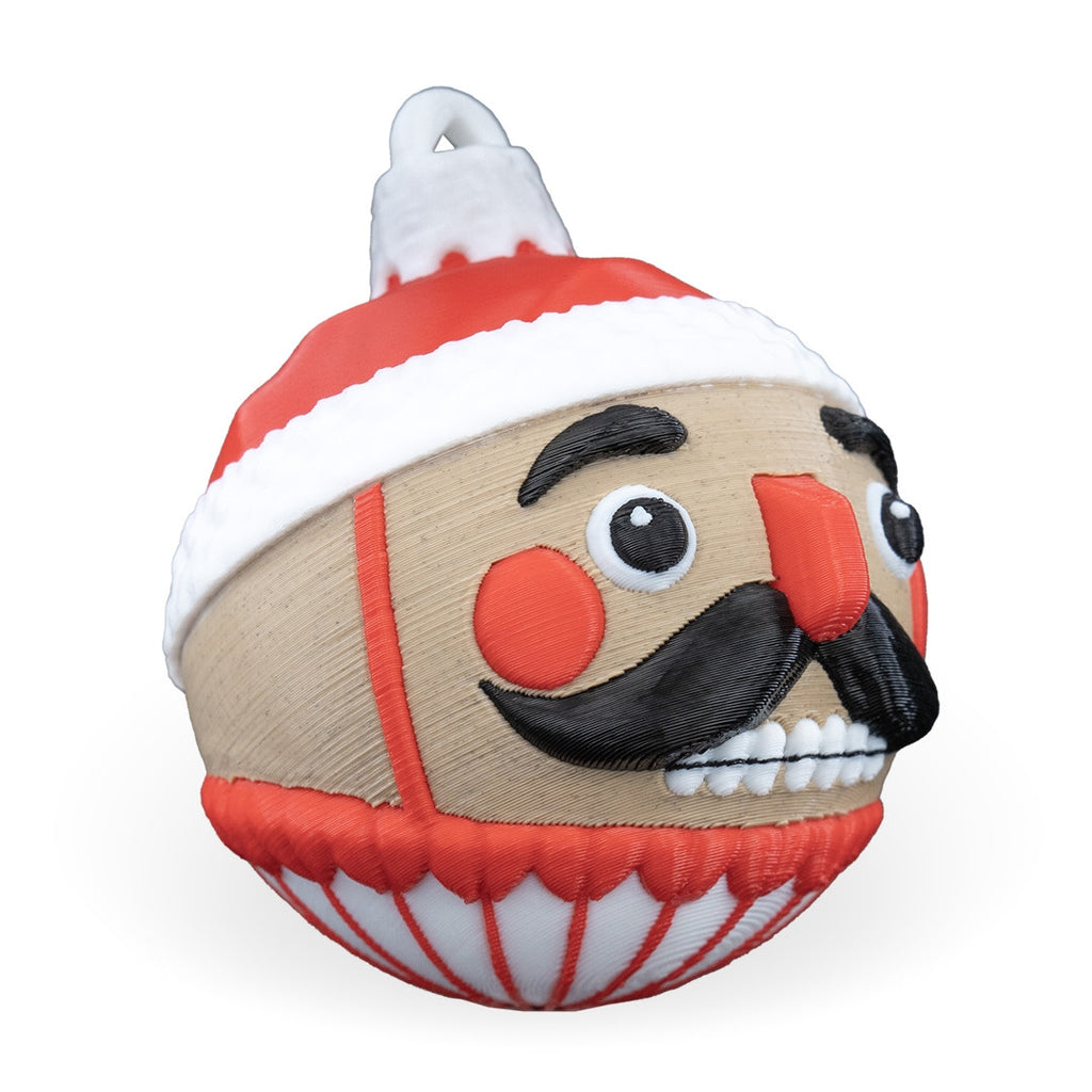 Nutcracker Christmas ornament angled to the right, showing the mustache, teeth and printed hanging loop, on a white background