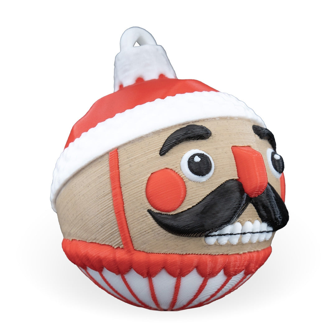 Nutcracker Christmas ornament angled to the right, showing the mustache, teeth and printed hanging loop, on a white background