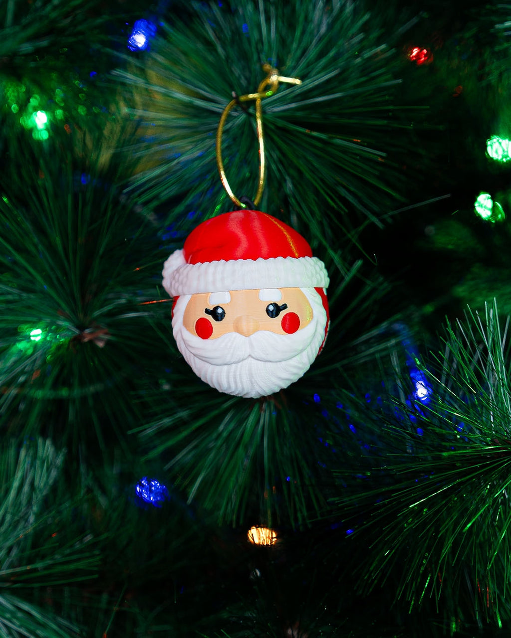 Santa Face Christmas ornament hanging on a lit Christmas tree