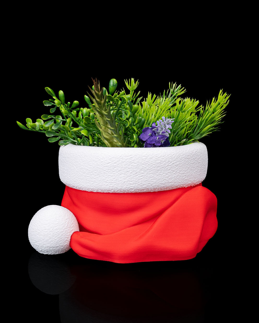 Santa hat candy bowl with greenery and holiday accents, red hat with white brim and pom-pom, on black background