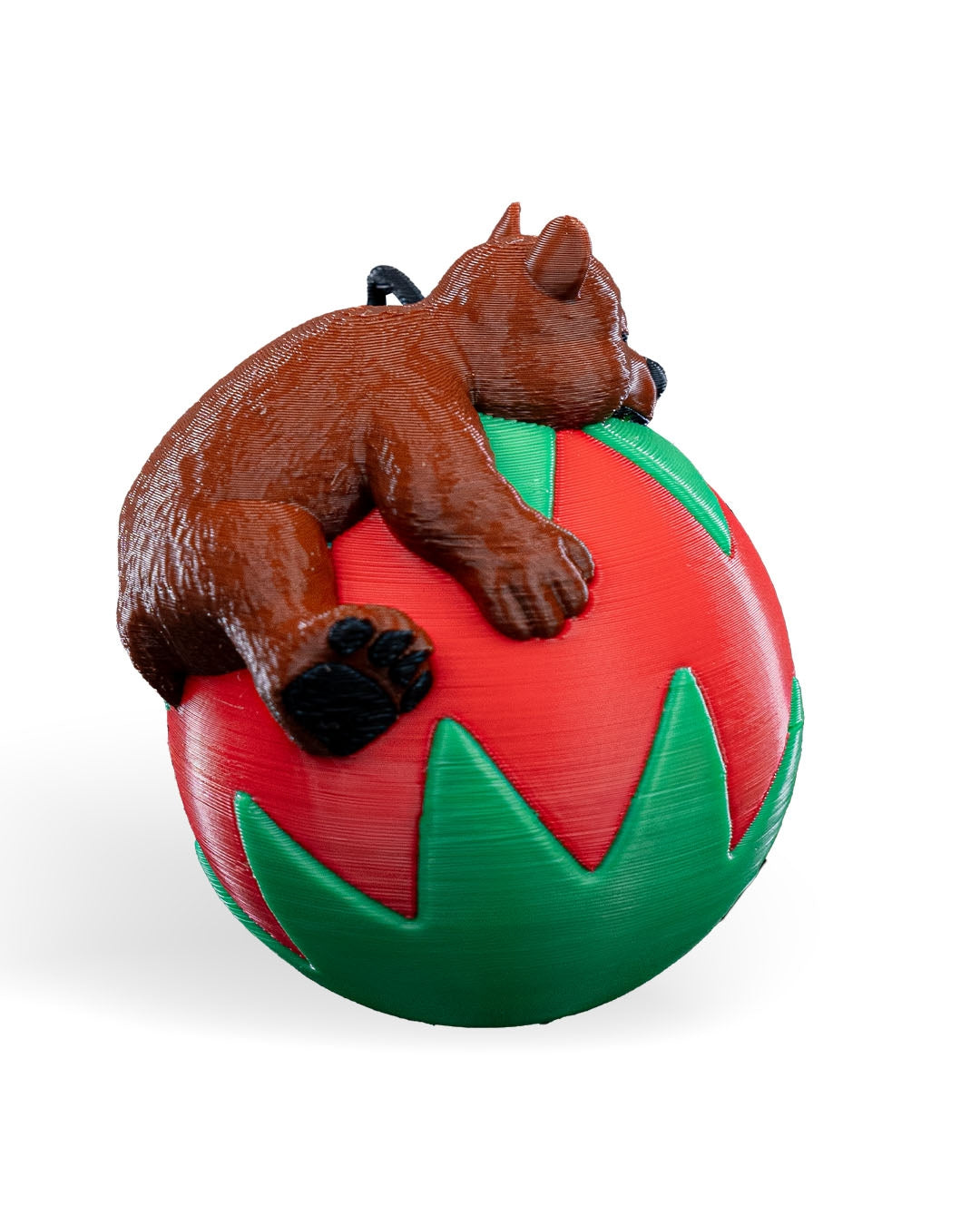 Sleeping Bear Christmas ornament turned to the side, showing the bear's textured fur and black paw pads, on a white background