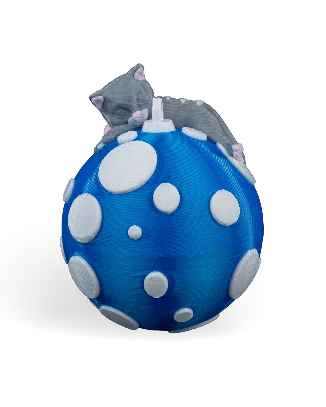 Sleeping Cat Christmas ornament, 3D printed, front view: gray kitten asleep on top of a blue ball with white polka dots, on a white background