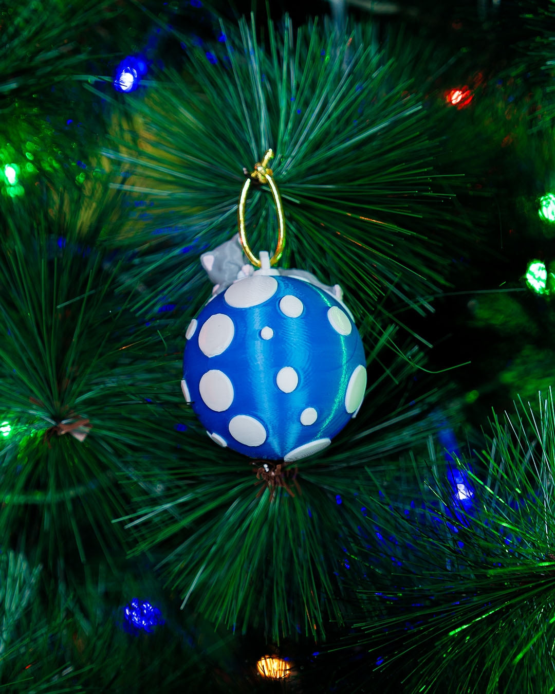 Sleeping Cat Christmas ornament hanging on a lit Christmas tree