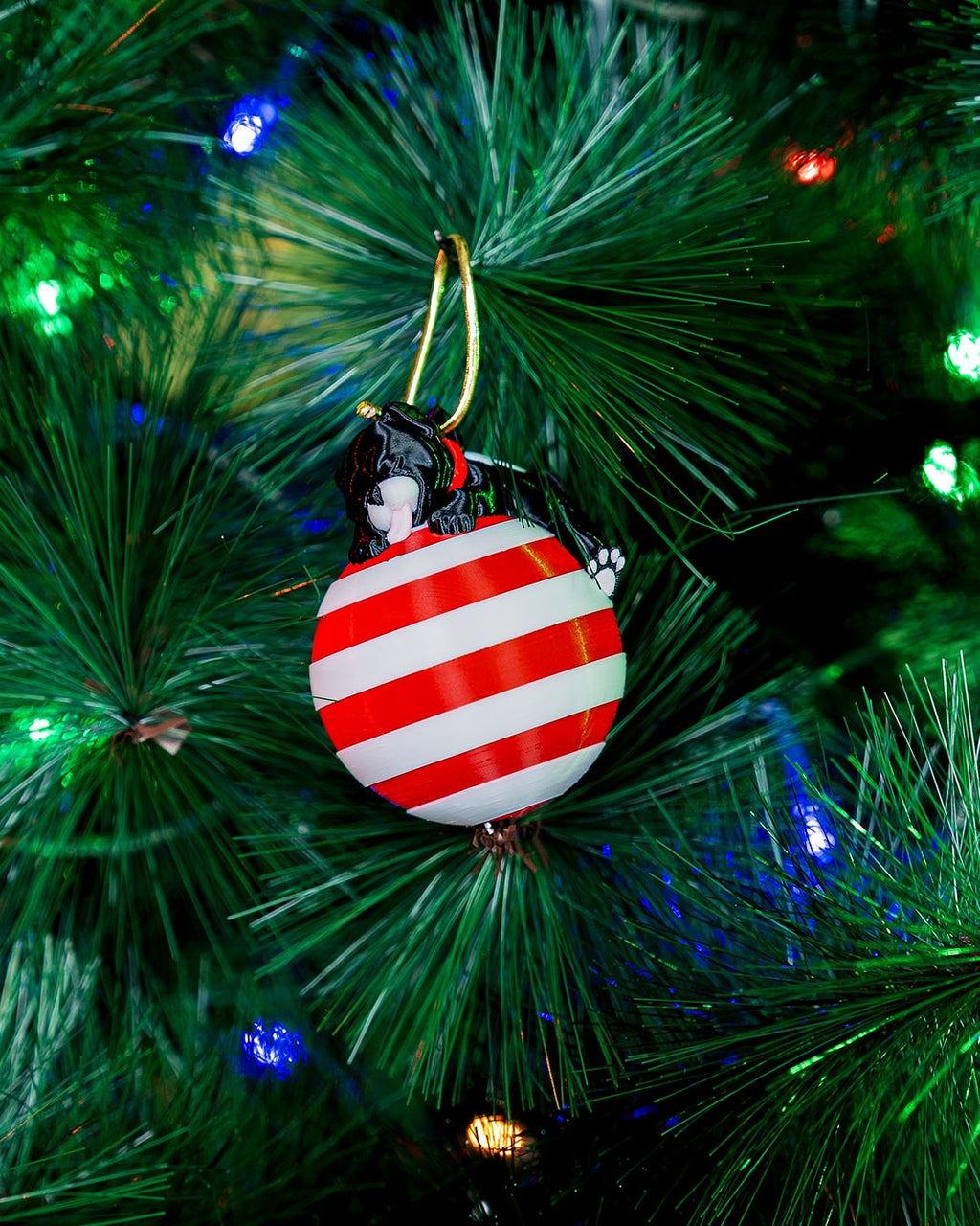 Sleeping Puppy Christmas ornament hanging on a lit Christmas tree