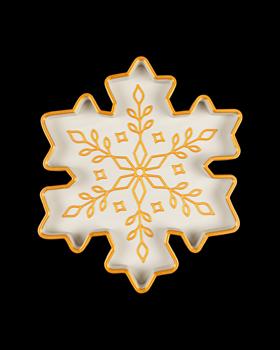 Top view of a white six-point snowflake tray with a gold rim and a gold branching leaf pattern, on a black background