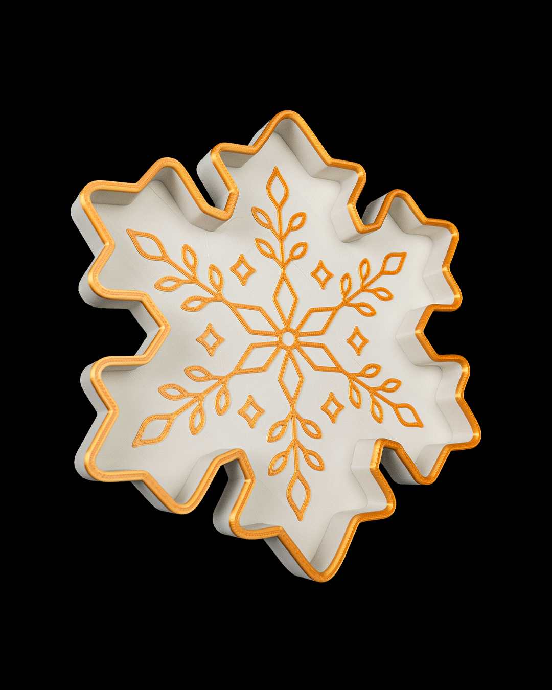 Angled view of the white and gold snowflake tray, on a black background