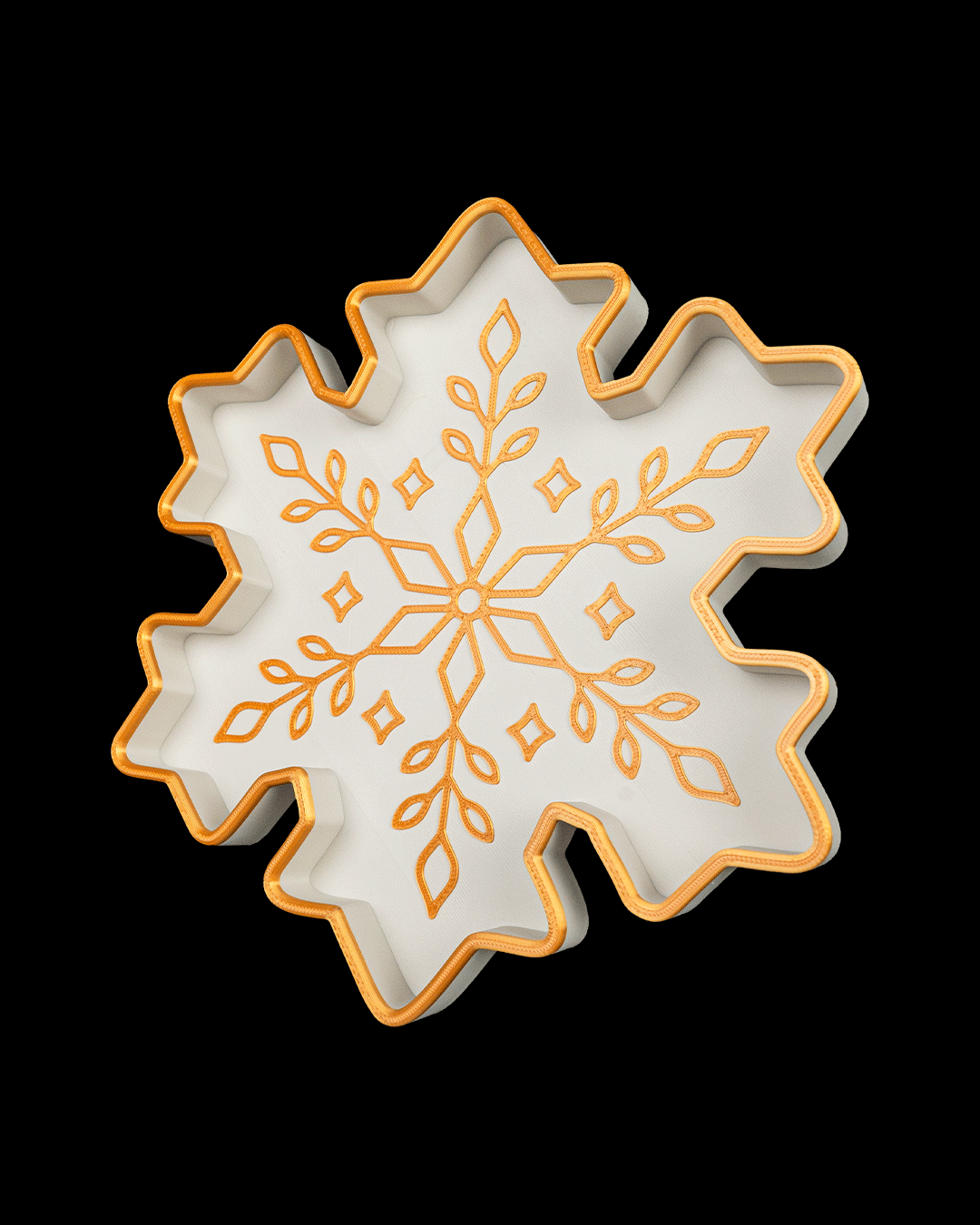 Another angled view of the white and gold snowflake tray, on a black background