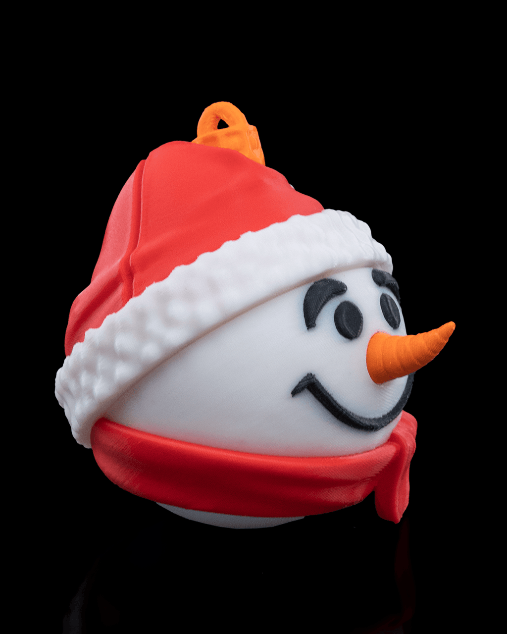Snowman Christmas ornament turned to the right, showing the carrot nose, red scarf and printed hanging loop, on a black background