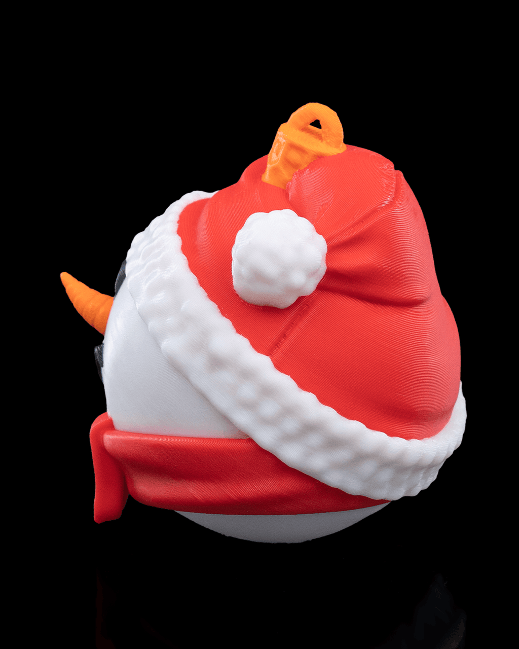 Side view of the Snowman Christmas ornament with red hat, white pompom and red scarf, on a black background